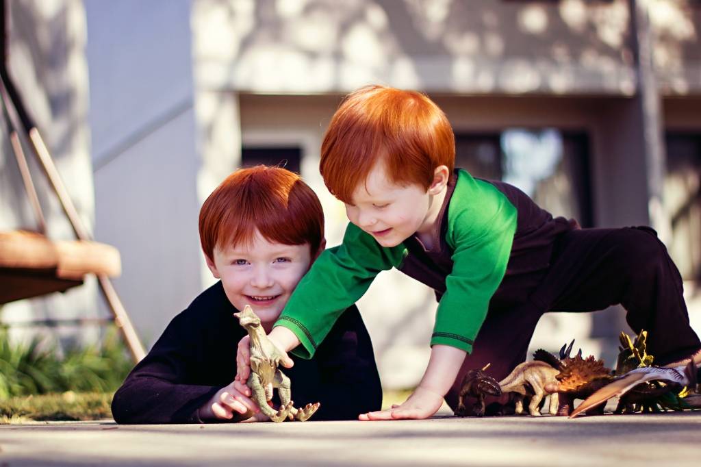 Crianças brincando com dinossauros Crianças brincando com dinossauros