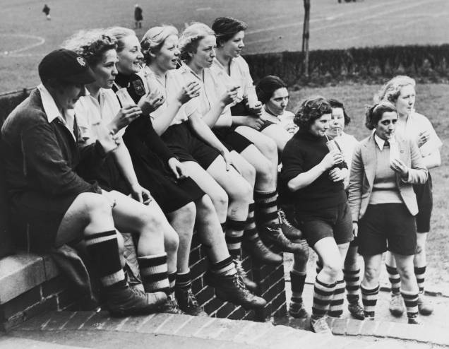 <span style="font-weight:400;">Durante seus anos de jogo, Preston Ladies quebrou uma série de barreiras. Tornou-se o primeiro time feminino a jogar uma partida internacional contra a equipe da França - evento que juntou mais de 25 mil espectadores - além de ter sido a primeira equipe a jogar sob os holofotes, na primeira partida noturna em 1920. Esta fotografia, de 1939, mostra a equipe durante o intervalo de um treino.</span> <span style="font-weight:400;">Durante seus anos de jogo, Preston Ladies quebrou uma série de barreiras. Tornou-se o primeiro time feminino a jogar uma partida internacional contra a equipe da França - evento que juntou mais de 25 mil espectadores - além de ter sido a primeira equipe a jogar sob os holofotes, na primeira partida noturna em 1920. Esta fotografia, de 1939, mostra a equipe durante o intervalo de um treino.</span>