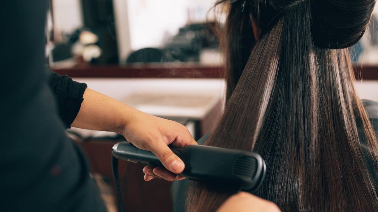 Cabeleireira fazendo chapinha em cabelo de cliente