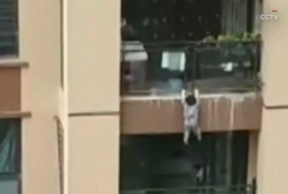 Menino pendurado na varanda de seu apartamento