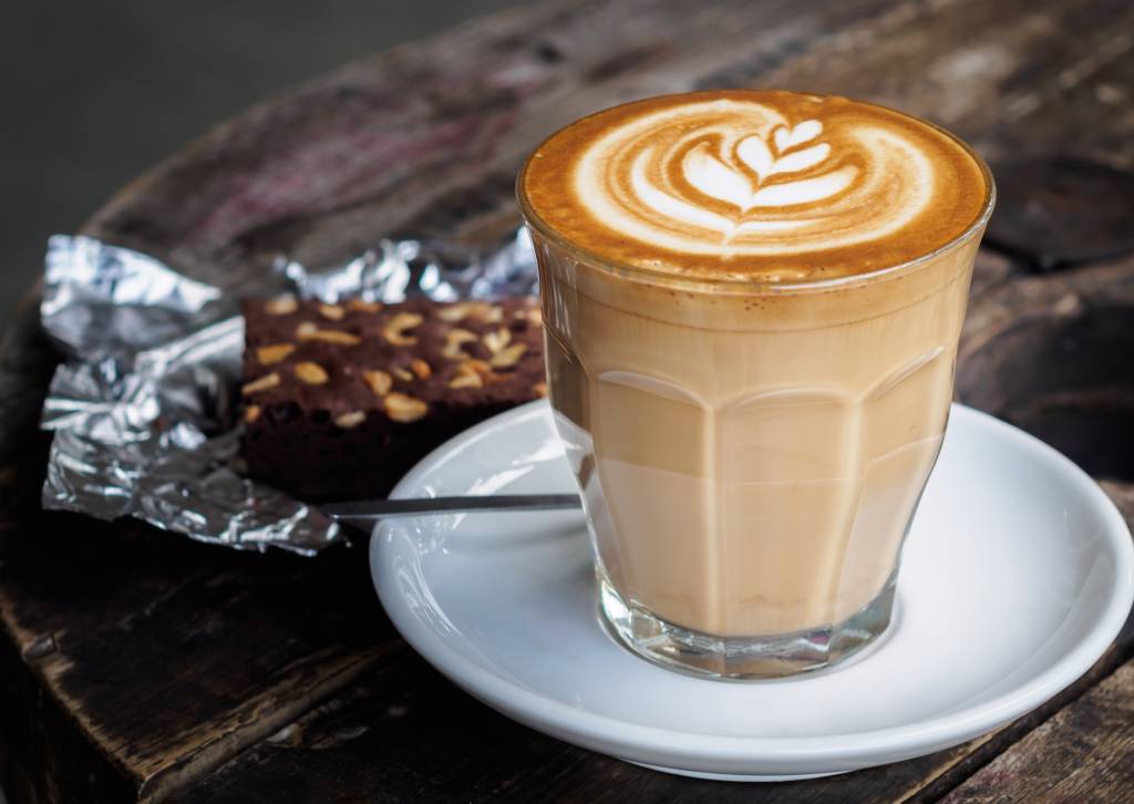 Hot latte coffee on old wooden table with brownie cake