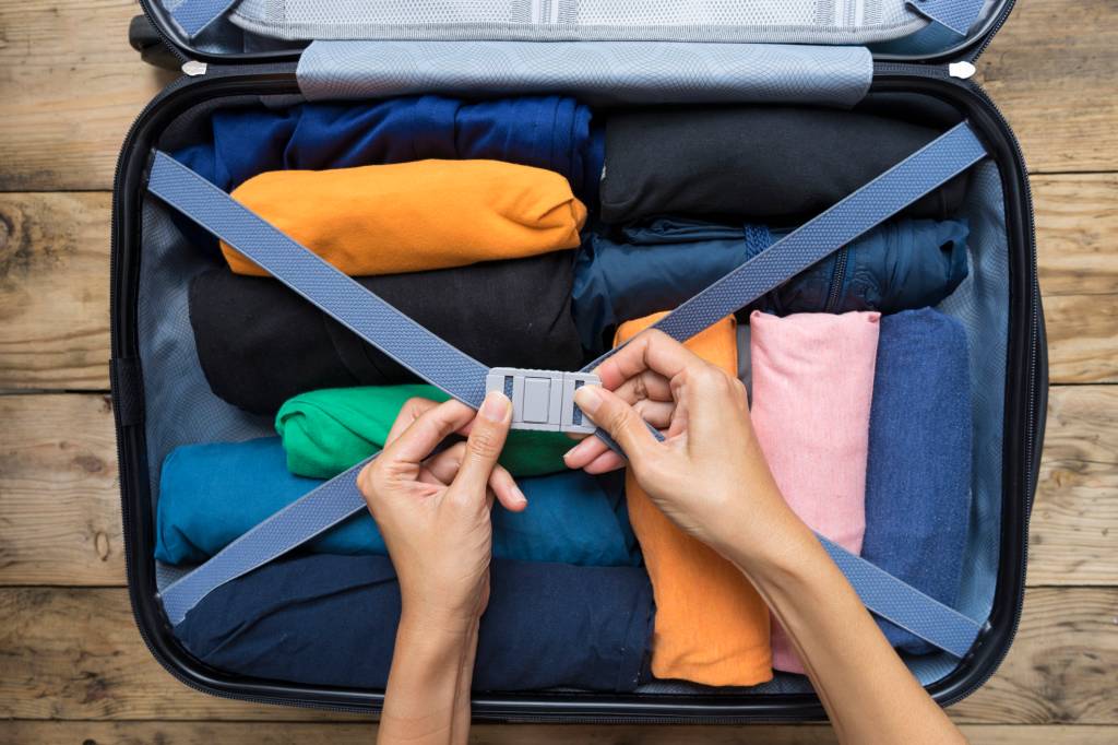 Enrolar as roupas economiza espaço na mala woman packing a luggage for a new journey
