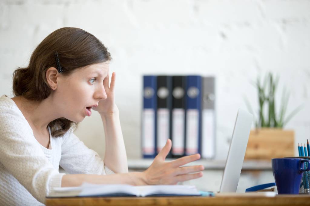 Young shocked business woman looking at laptop computer