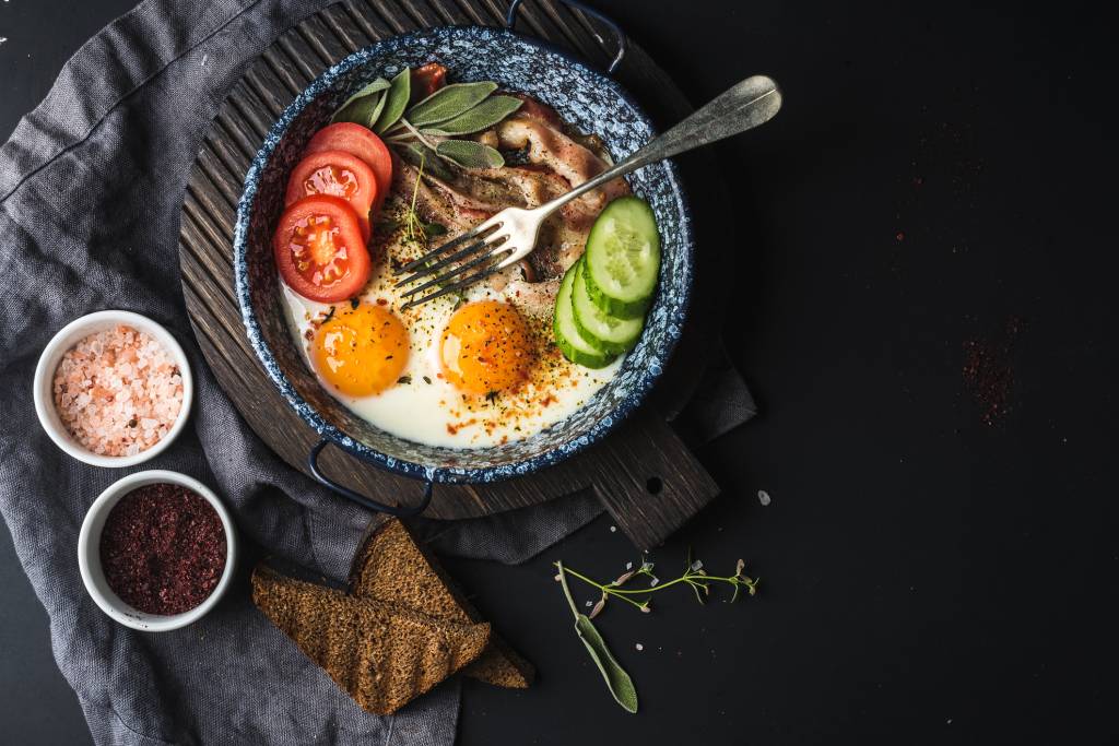 Breakfast set. Pan of fried eggs with bacon, fresh tomato