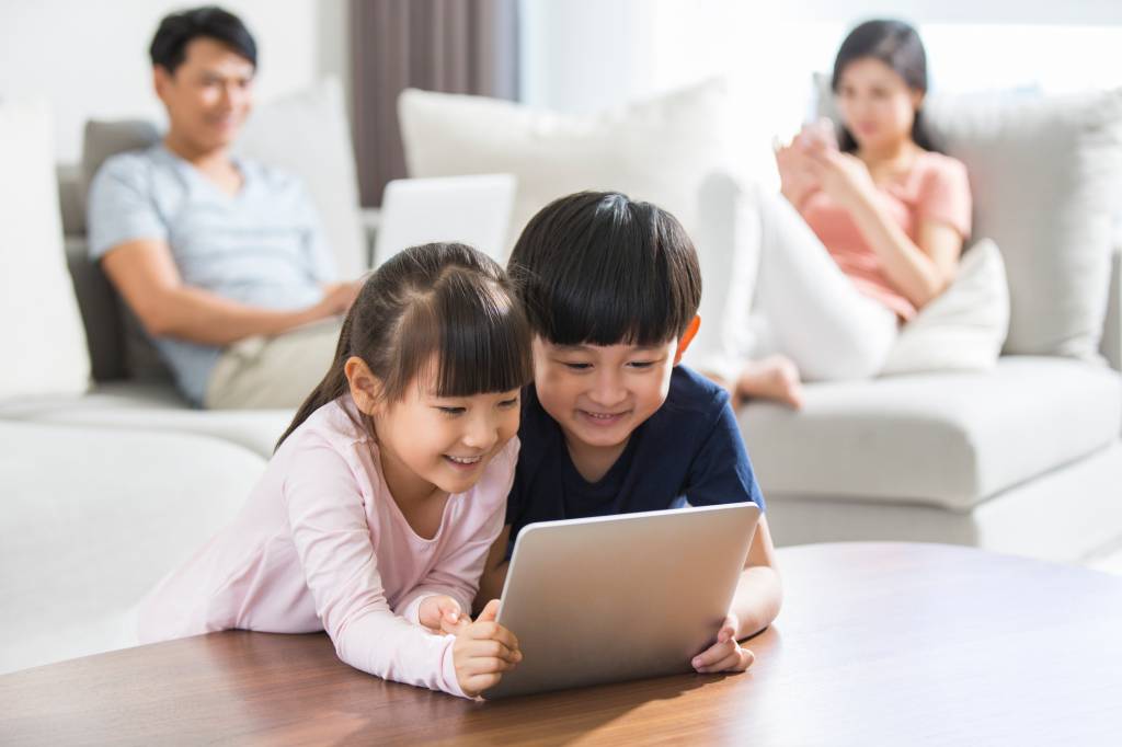 Família Happy young family using digital gadgets at home