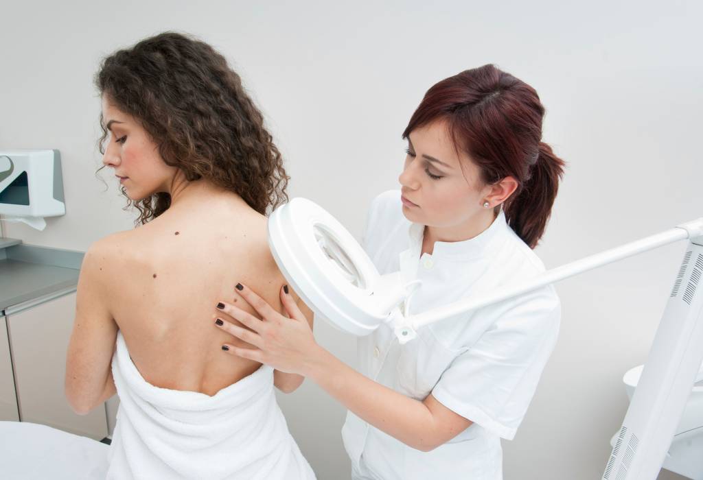 Young woman’s back being examined at a dermatologists