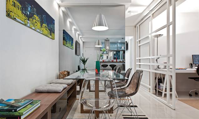 <span>A fim de poupar espaço, o arquiteto deu dupla função ao rack, que se prolonga e vira banco. Almofadas demarcam os assentos”, explica. </span>Para não pesar no ambiente, ele escolheu uma mesa com tampo de vidro e base de madeira em cruz. Seguindo a proposta de leveza, as cadeiras são de acrílico incolor e preto. Projeto de Daniel Tesser. <span>A fim de poupar espaço, o arquiteto deu dupla função ao rack, que se prolonga e vira banco. Almofadas demarcam os assentos”, explica. </span>Para não pesar no ambiente, ele escolheu uma mesa com tampo de vidro e base de madeira em cruz. Seguindo a proposta de leveza, as cadeiras são de acrílico incolor e preto. Projeto de Daniel Tesser.