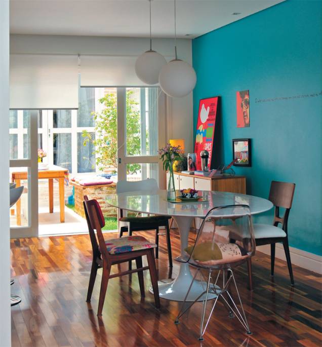 Na casa da designer Ana Maria Mouawad Queiroga, a mesa de jantar recebeu irreverentes cadeiras diferentes. A parede turquesa recebe a iluminação que vem pela porta de vidro (que substitui a janela) e uma cortina rolô controla a luminosidade do ambiente. Na casa da designer Ana Maria Mouawad Queiroga, a mesa de jantar recebeu irreverentes cadeiras diferentes. A parede turquesa recebe a iluminação que vem pela porta de vidro (que substitui a janela) e uma cortina rolô controla a luminosidade do ambiente.
