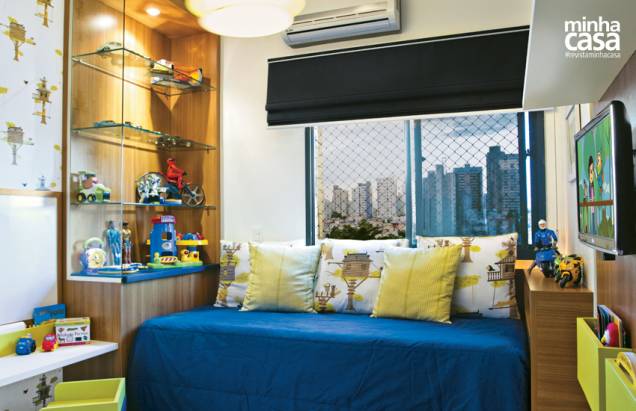 A decoração alegre e com cara de menino deve muito à combinação de cores. A base azul-marinho, presente na colcha e na cortina, foi quebrada com toques verde-limão de alguns elementos, como a estampa do papel de parede, que se repete nas almofadas. “Enxoval, almofadas e luminária são de algodão puro, indicado para uso infantil”, explica a arquiteta. Projeto da arquiteta Camila Moraes. A decoração alegre e com cara de menino deve muito à combinação de cores. A base azul-marinho, presente na colcha e na cortina, foi quebrada com toques verde-limão de alguns elementos, como a estampa do papel de parede, que se repete nas almofadas. “Enxoval, almofadas e luminária são de algodão puro, indicado para uso infantil”, explica a arquiteta. Projeto da arquiteta Camila Moraes.