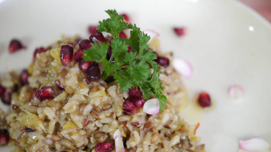 Salada de Grãos, Romã e Laranja – Ceia saudável Na foto, há uma mistura de arroz e trigo cozidos com sementes de romã e uma folha de salsinha no topo, para decorar
