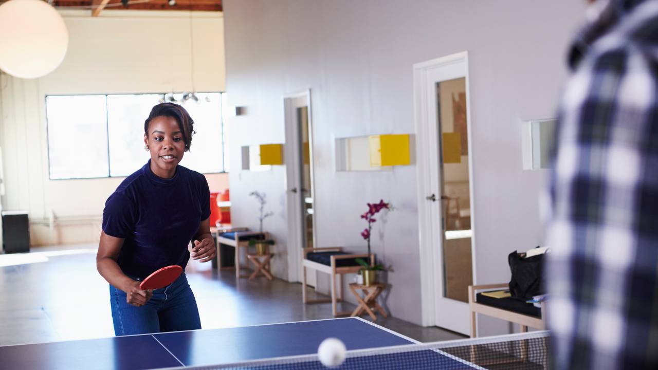 mulher jogando ping pong no escritório