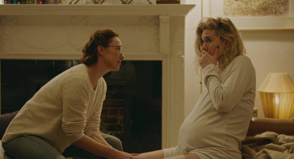 PIECES OF A WOMAN: (L to R) Molly Parker as Eva and Vanessa Kirby as Martha. Duas mulheres sentadas olham uma para outra. Uma delas está grávida e com a mão na boca.