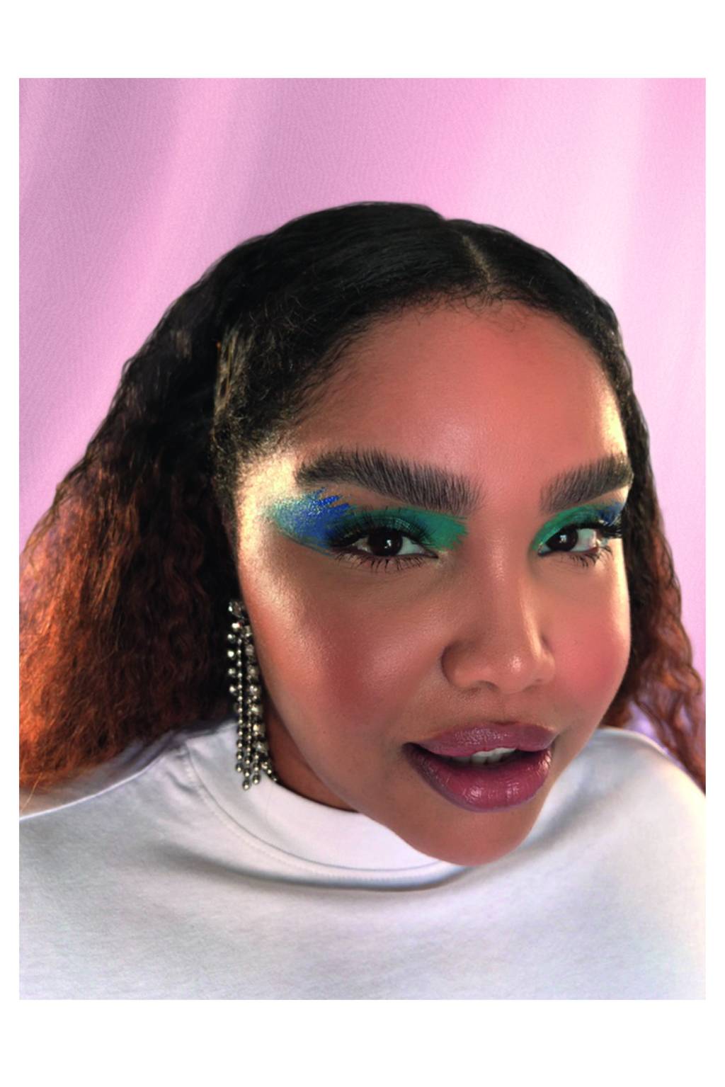 BELEZA3 Mulher com os olhos maquiados com sombra azul e unhas pintadas de amarelo olha para a câmera