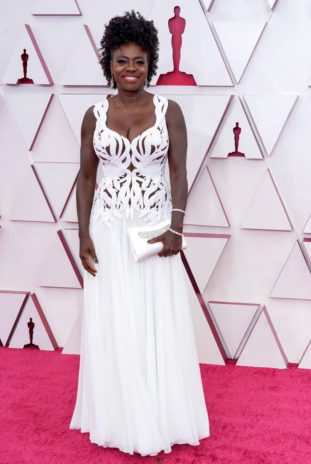 93rd Annual Academy Awards – Arrivals Viola é uma mulher negra com cabelos castanhos cacheados presos. Ela usa um vestido branco com recortes por todo o corpete e saia fluida.