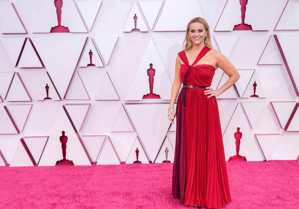 93rd Annual Academy Awards – Arrivals Reese é uma mulher branca, loira, com um vestido em vários tons de vermelho com a cintura marcada por um cinto preto