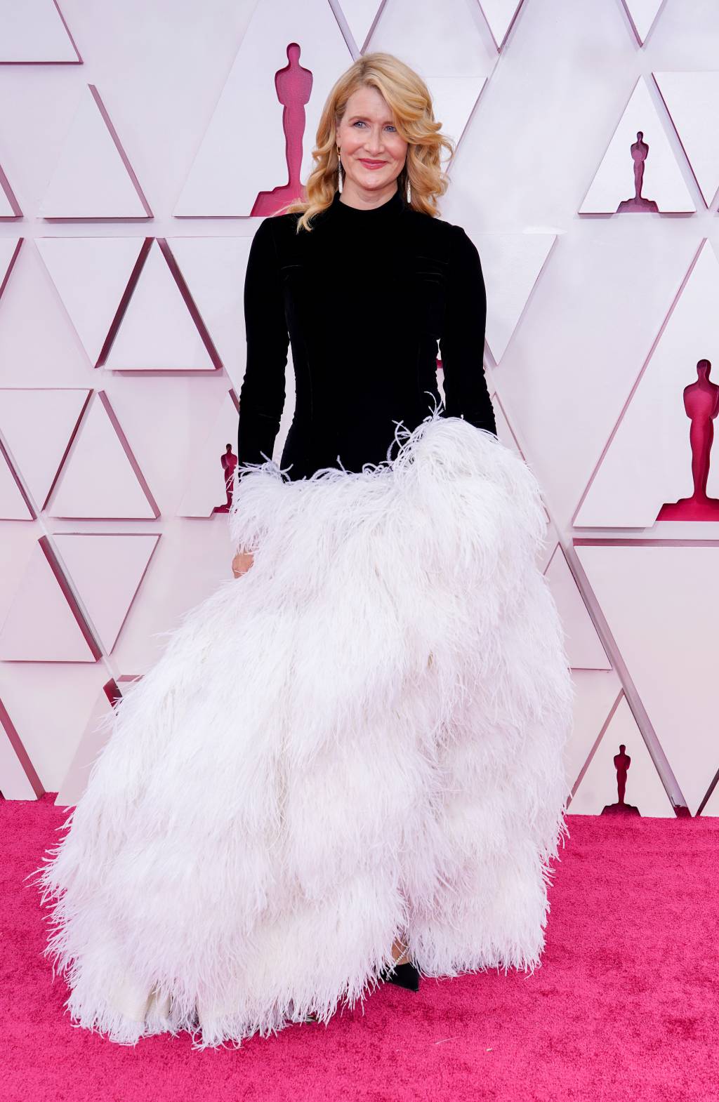 93rd Annual Academy Awards – Arrivals Laura é uma mulher branca com cabelo loiro. O vestido de mangas compridas pretas tem uma volumosa saia de plumas brancas
