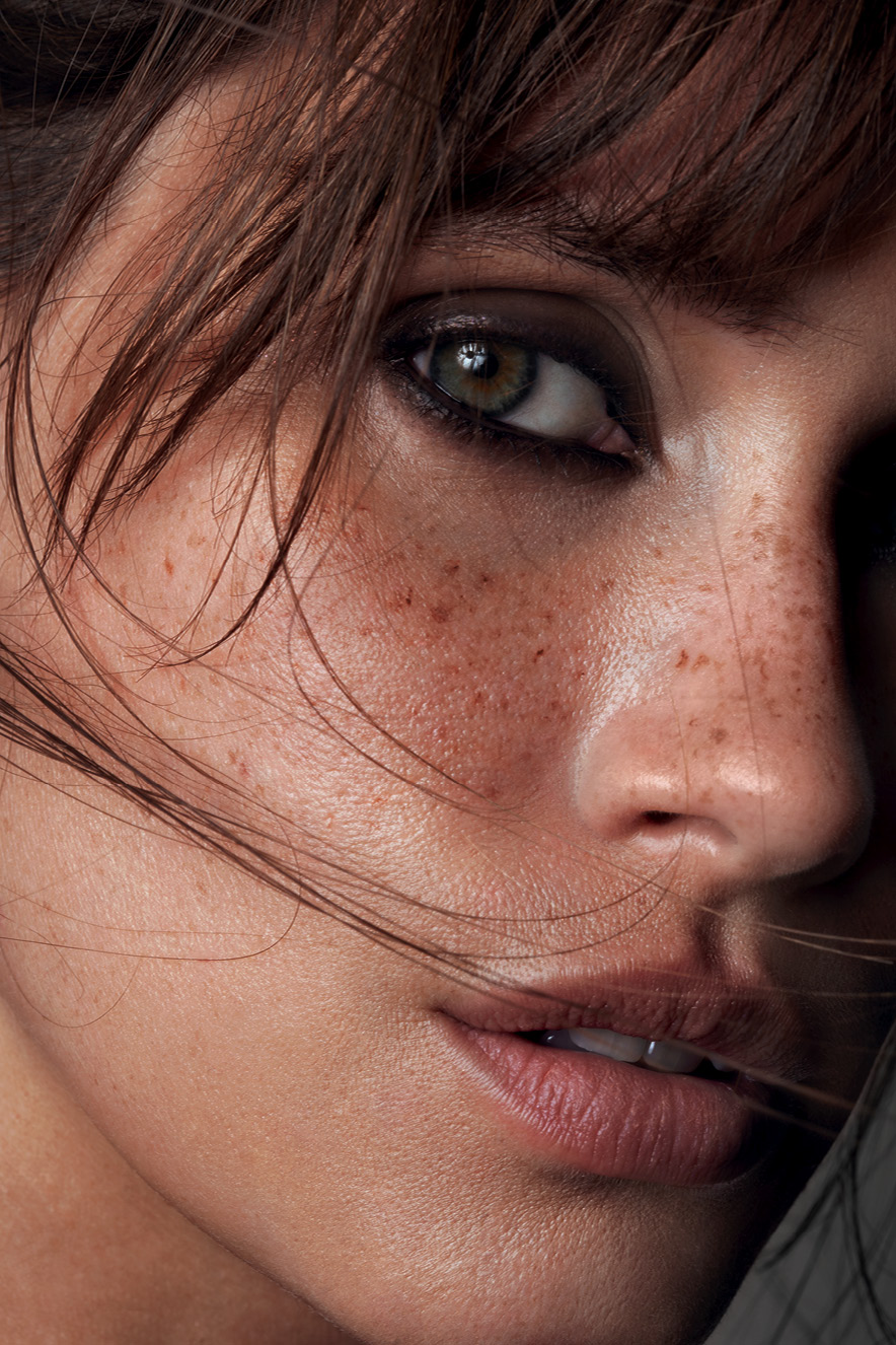 Em retrato, mulher maquiada com pele natural e olhos marcados por l&aacute;pis preto olha para a c&acirc;mera