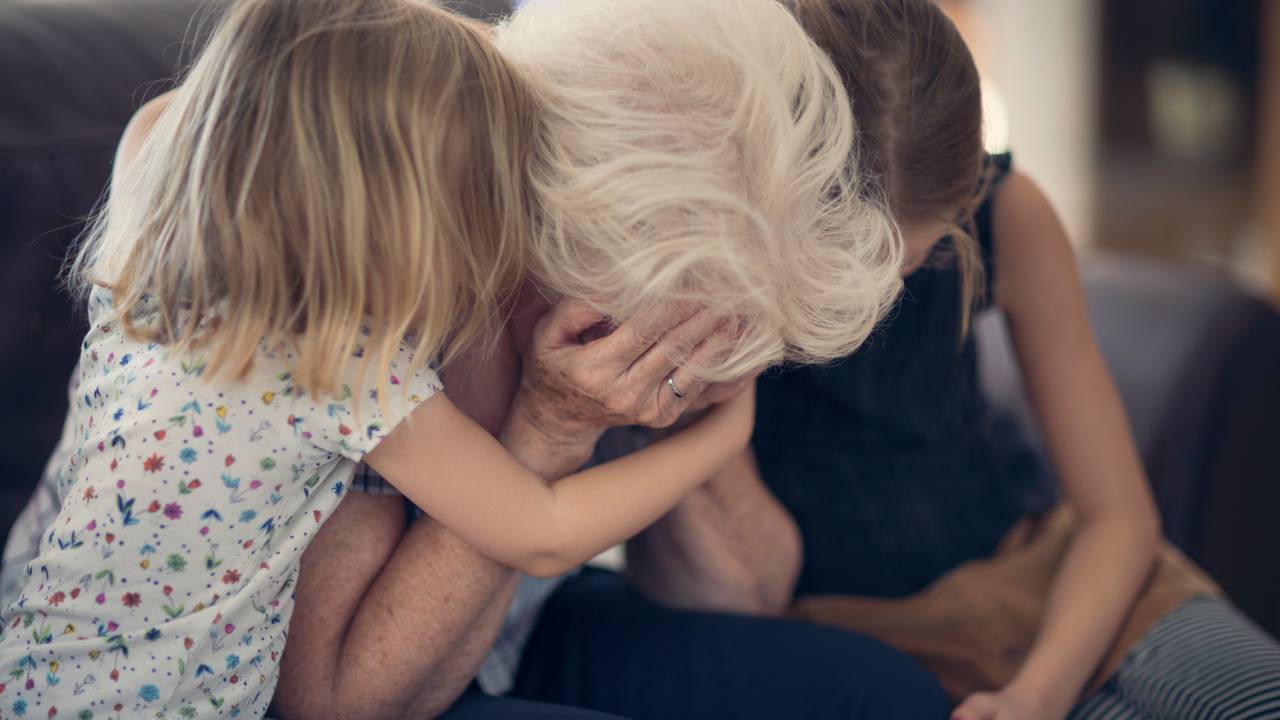 Mulher chora e recebe abraço de duas meninas