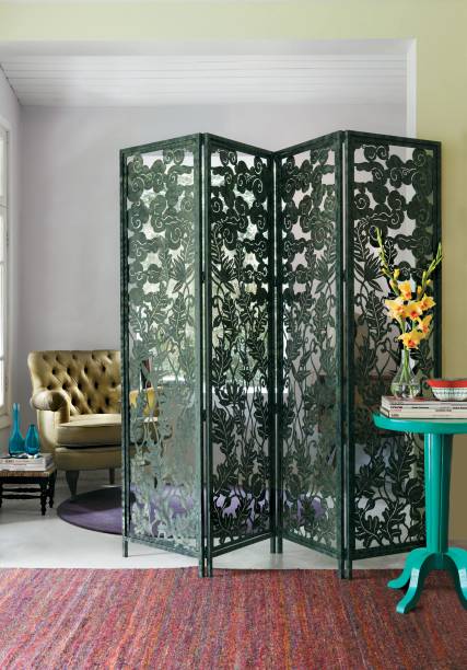 Área de leitura com biombo de ferro rendado verde-militar da L'Oeil, projeto da designer de interiores Neza Cesar