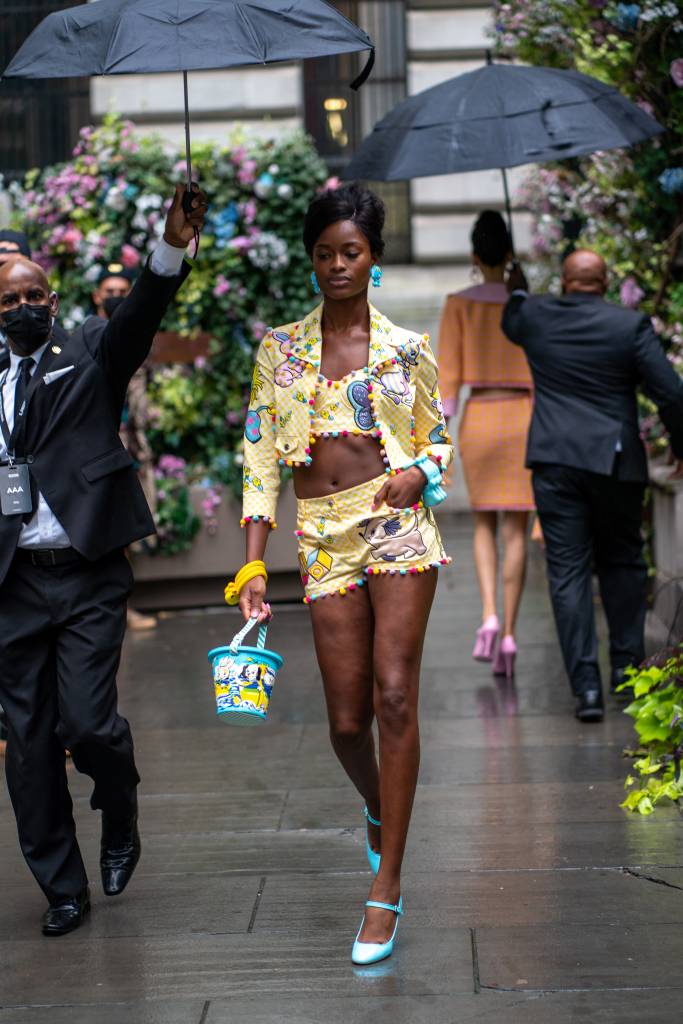 Moschino SS22 – September 2021 – New York Fashion Week: The Shows Modelo anda com look colorido e um balde na mão.