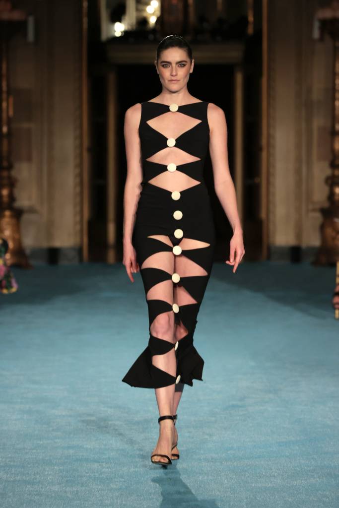 Christian Siriano SS2022 NYFW Show – Runway Modelo na passarela com um vestido preto longo e aberto com botões.