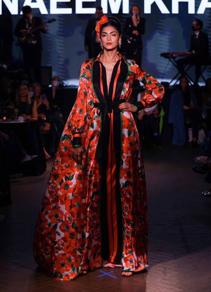 Runway 7 Debuts Spring/Summer 2022 Collections – Naeem Khan Modelo na passarela com um look vermelho e flor na cabeça