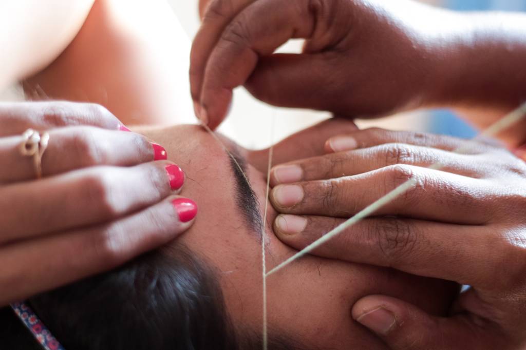 Cropped Hands Of Beautician Threading Woman Eyebrows foto