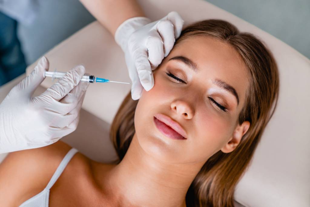 Young woman gets beauty facial injections in salon bioestimulador de colágeno