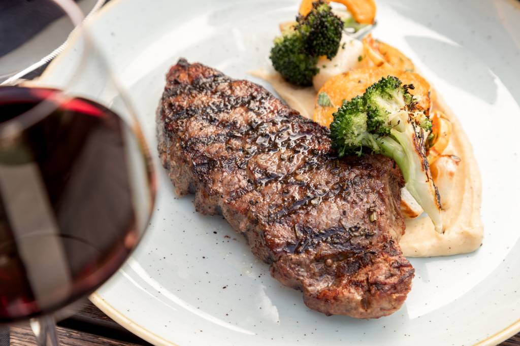 Prato de carne com brócolis e taça de vinho Prato de carne com brócolis e taça de vinho
