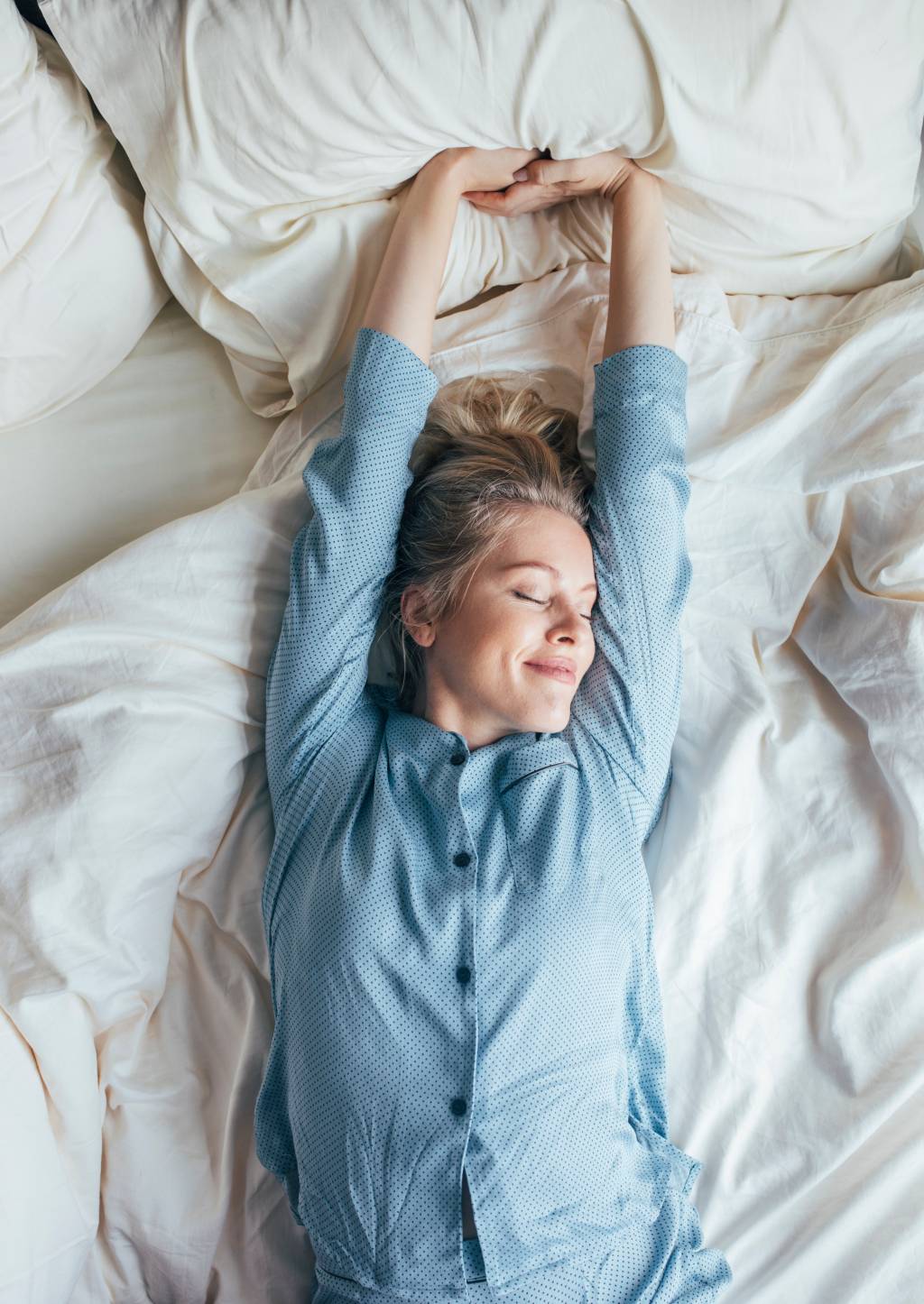 Weekend Mornings: Happy Blonde Woman in Blue Pyjamas Stretches after Waking Up Weekend Mornings: Happy Blonde Woman in Blue Pyjamas Stretches after Waking Up