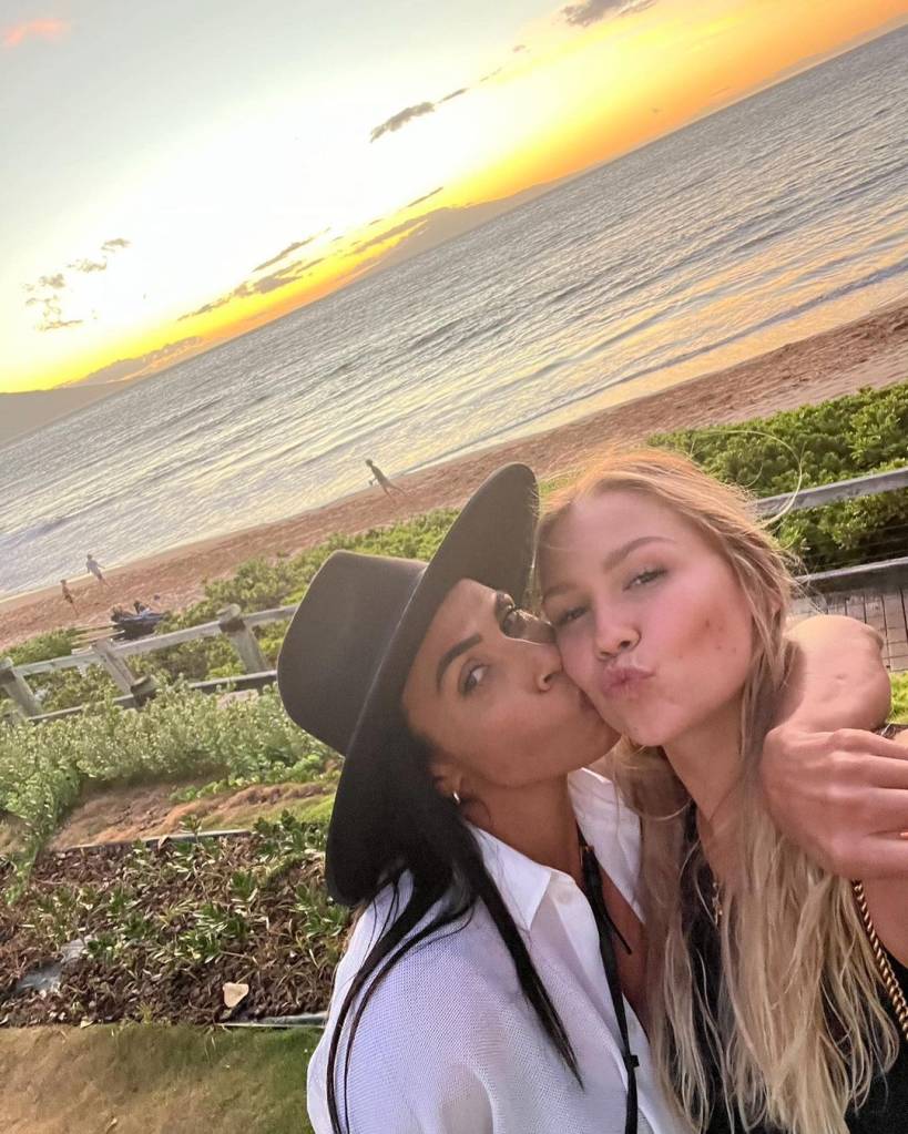 Marta e Carrie posando juntas e abraçadas em um pôr-do-sol na praia