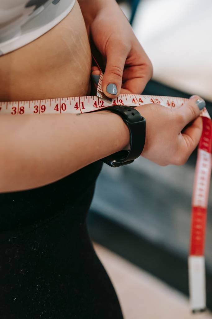 ozonioterapia-perda-peso-mitos-verdades-dermatologia Mulher medindo sua cintura com uma fita métrica