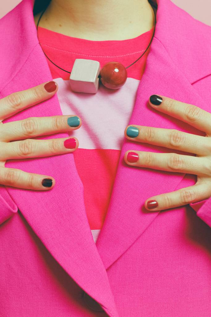 Mulher vestida com blazer rosa destacando suas unhas