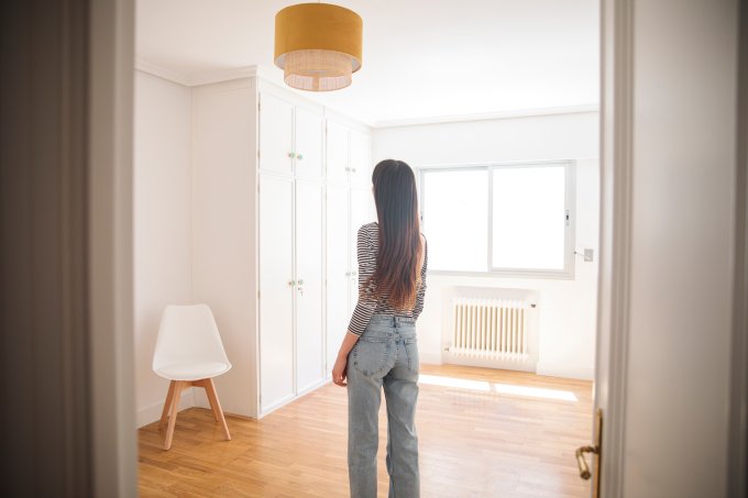 young woman in an empty apartment looking around