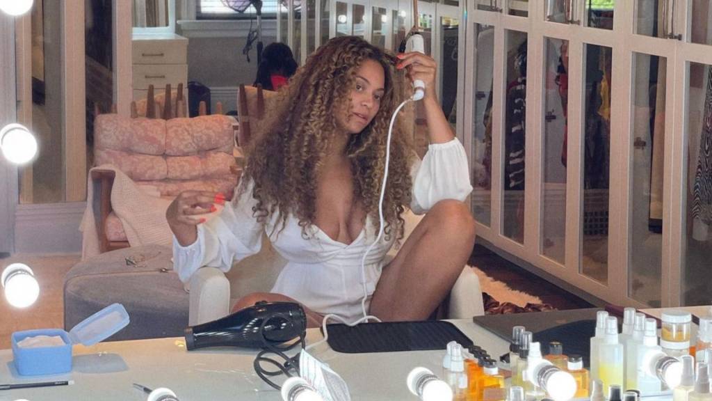 Beyoncé-Cécred-nova-linha-de-produtos-capilares-lançamento-cabelos-cacheados-crespos Beyoncé sentada em frente a uma penteadeira utilizando um babyliss