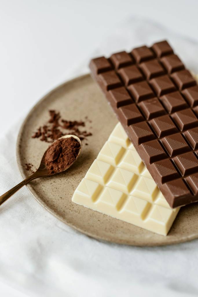 Barras de chocolate e uma colher com chocolate em pó