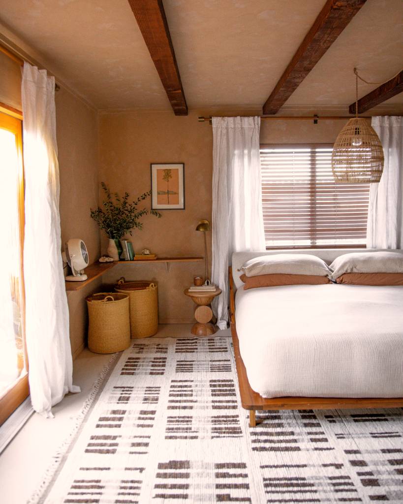 O espaço, disponível no AirBnb tem um quarto no tom Mocha Mousse, uma cama de casal, um tapete preto e branco e iluminação natural
