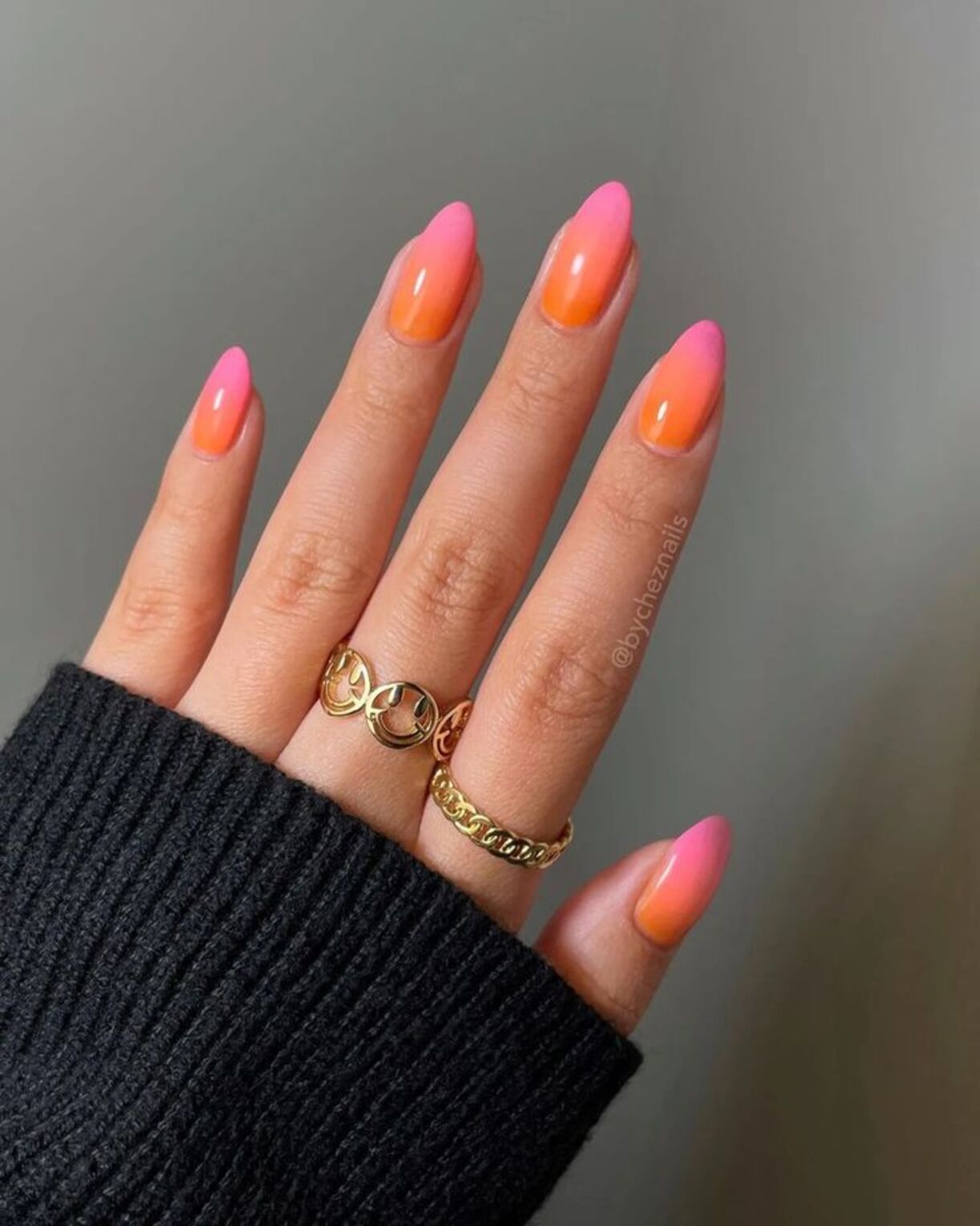 Unhas com esmalta&ccedil;&atilde;o que imita o p&ocirc;r-do-sol nos tons de laranja e rosa.