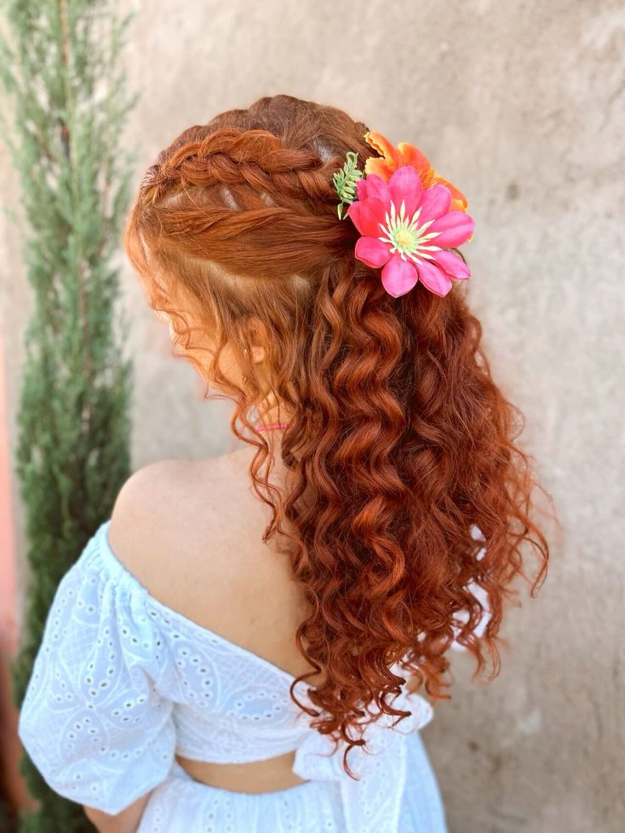 Imagem de cabelos ruivos presos com tran&ccedil;a e flor rosa.