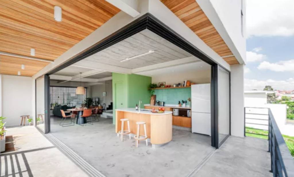 Sala e área gourmet podem ser abertas para a área externa e fechada com esquadrias quando preciso, mantendo a iluminação e vista | Projeto do escritório Studio Dlux