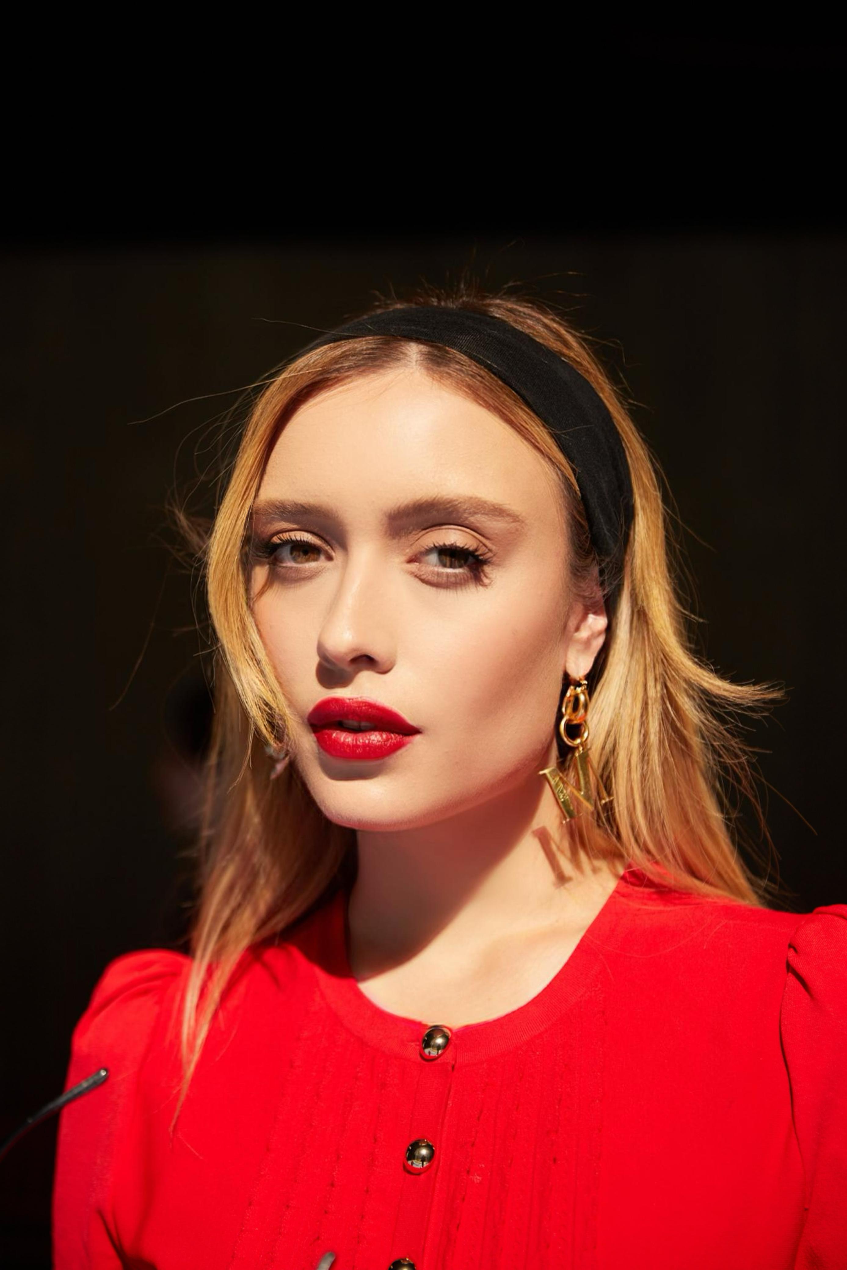 Mulher loira com make leve e batom vermelho.