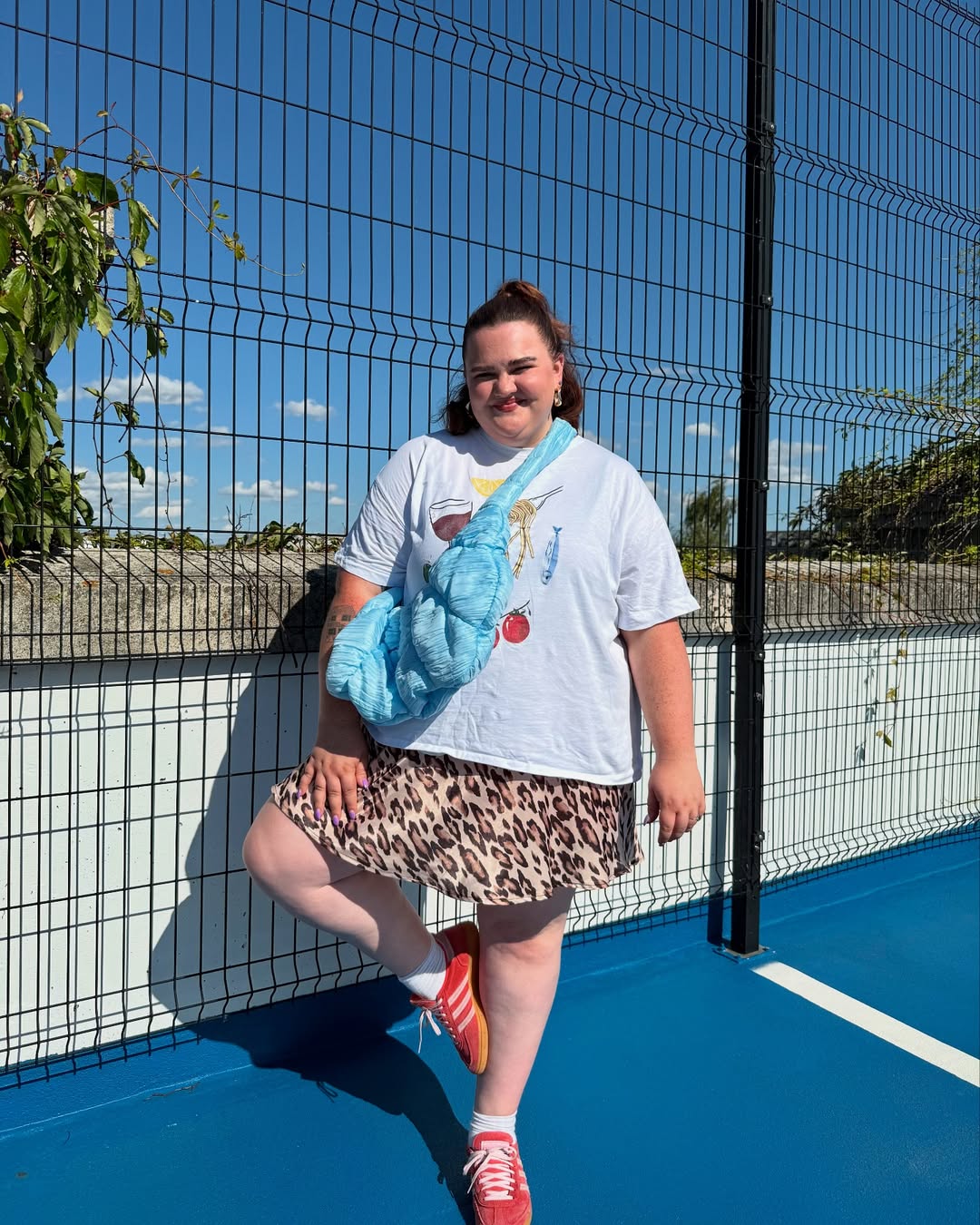 Look plus size com saia animal print, camiseta branca e t&ecirc;nis vermelho