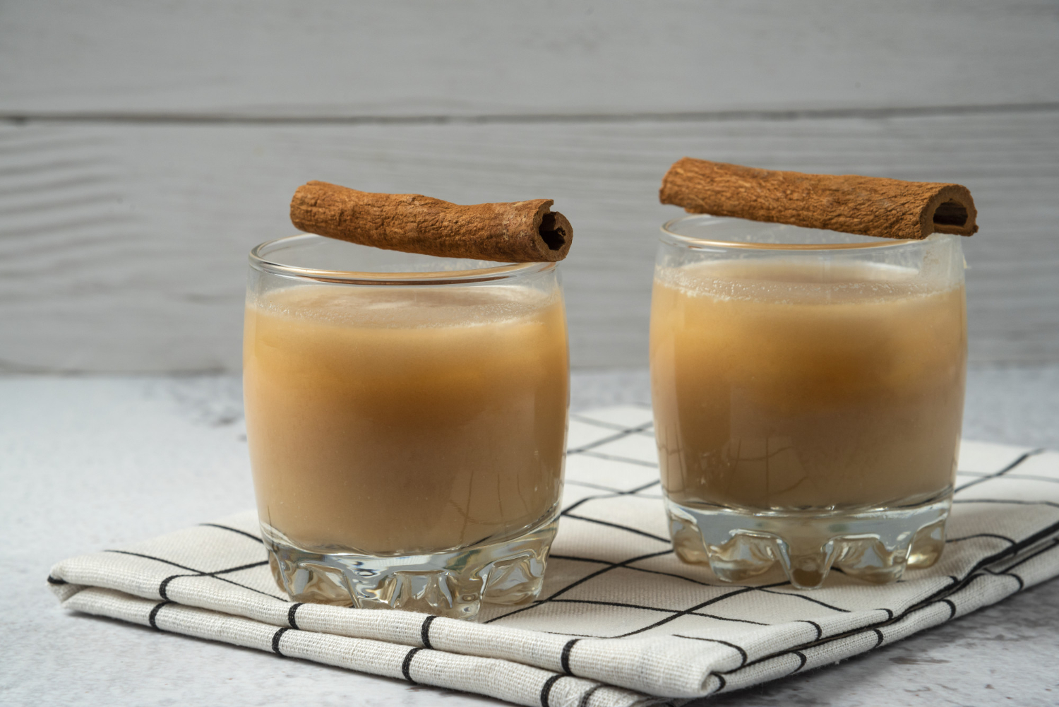 X&iacute;cara ou copo com o Leite Dourado (Golden Milk), uma bebida quente de cor amarelo-intenso. A superf&iacute;cie do shot pode estar salpicada com canela em p&oacute;, sugerindo a presen&ccedil;a das especiarias. Esta imagem foca no shot de leite vegetal, c&uacute;rcuma e pimenta-do-reino, destacando a curcumina com sua potente a&ccedil;&atilde;o imunomoduladora e antioxidante para indexar a receita completa na mat&eacute;ria de shots de imunidade.