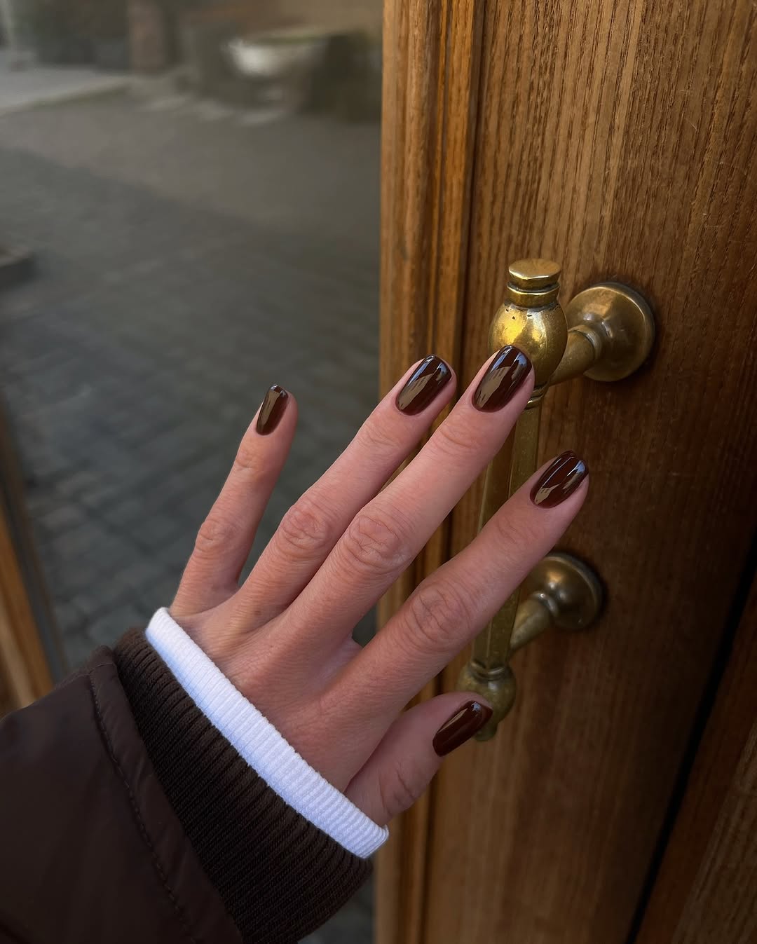 Unhas em tom marrom escuro garantem um visual elegante e atemporal