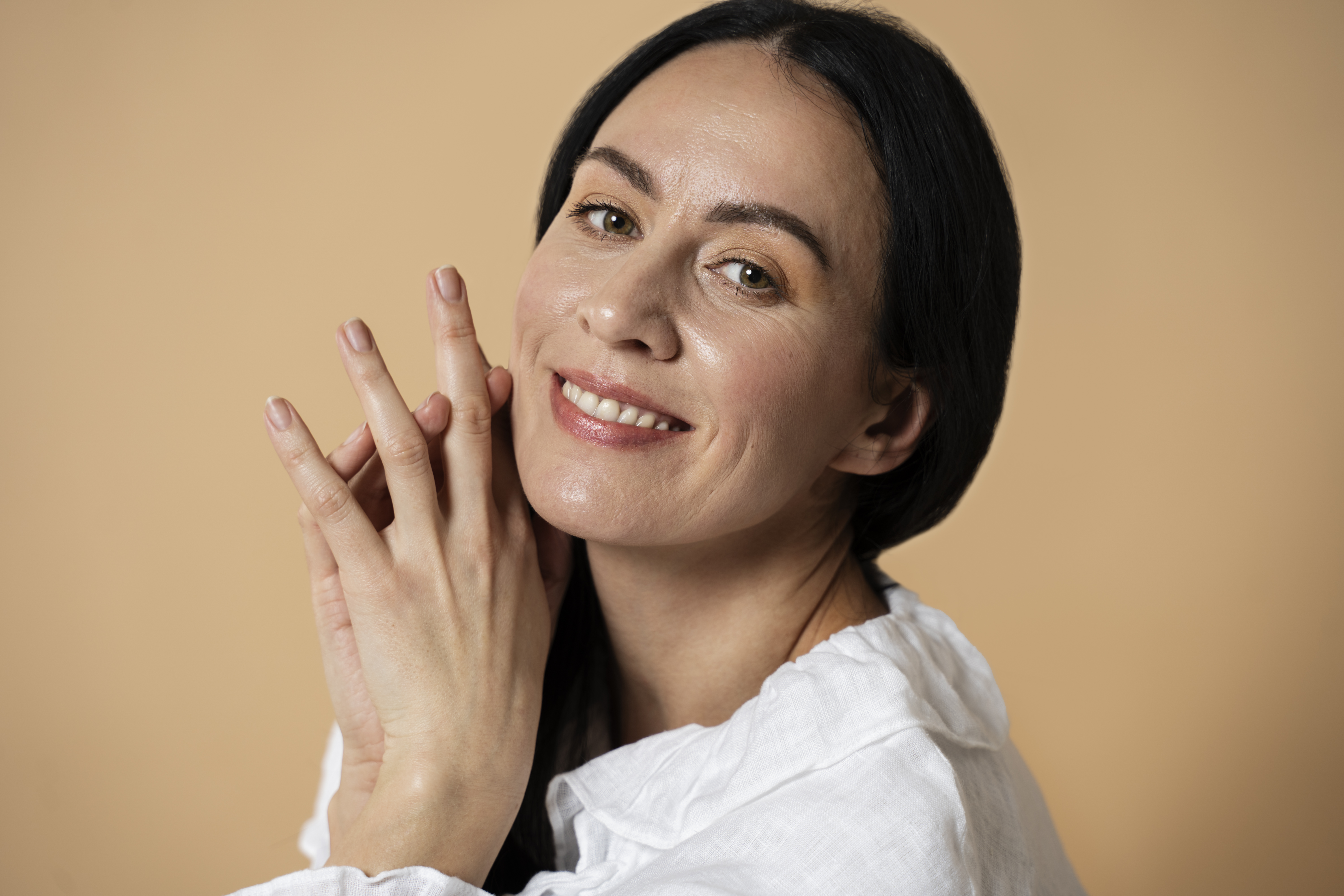 Foto de uma mulher morena com a pele branca e madura. Ela usa sombra dourada