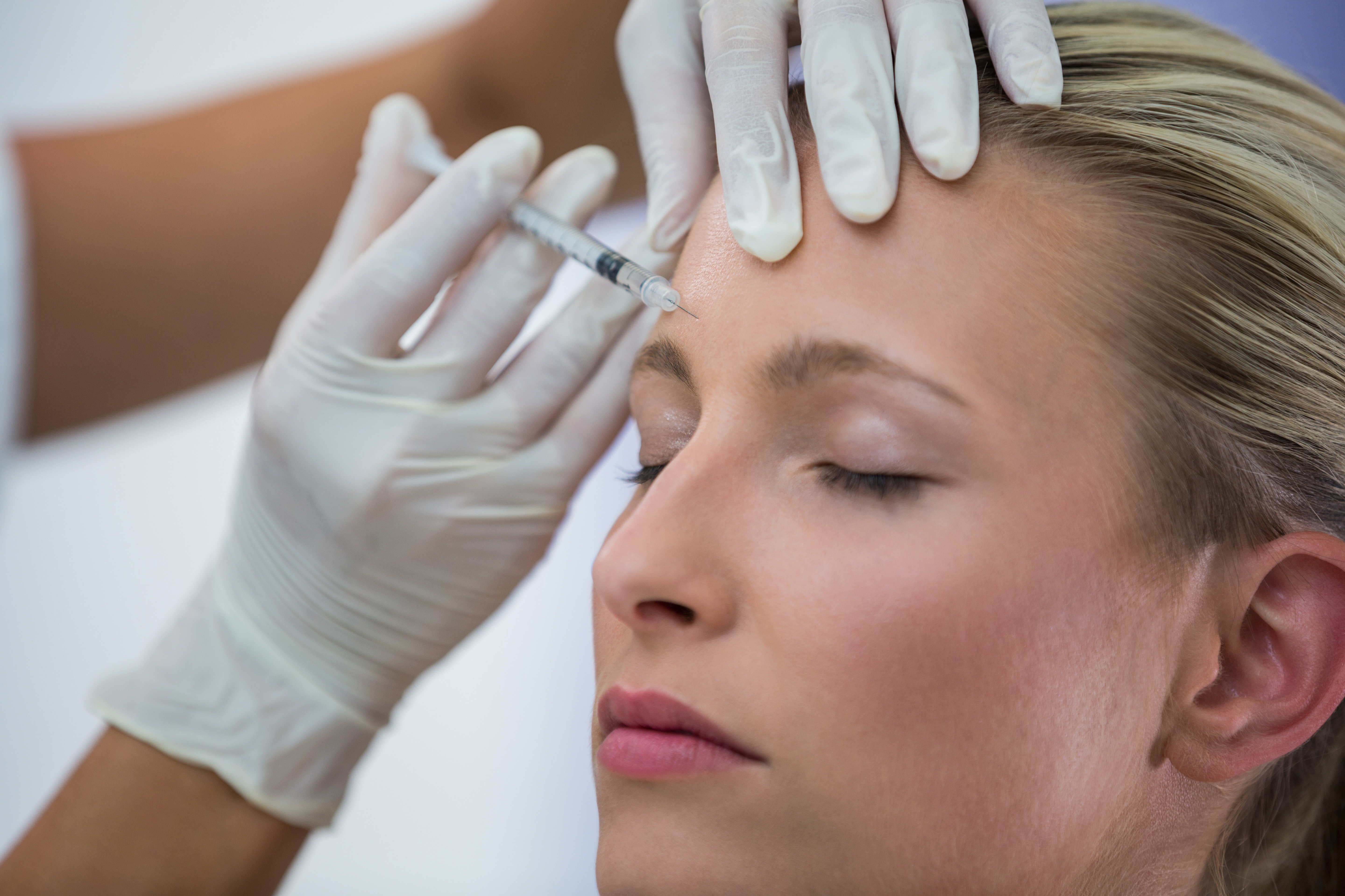 Foto de uma mulher jovem recebendo a aplica&ccedil;&atilde;o de botox no rosto