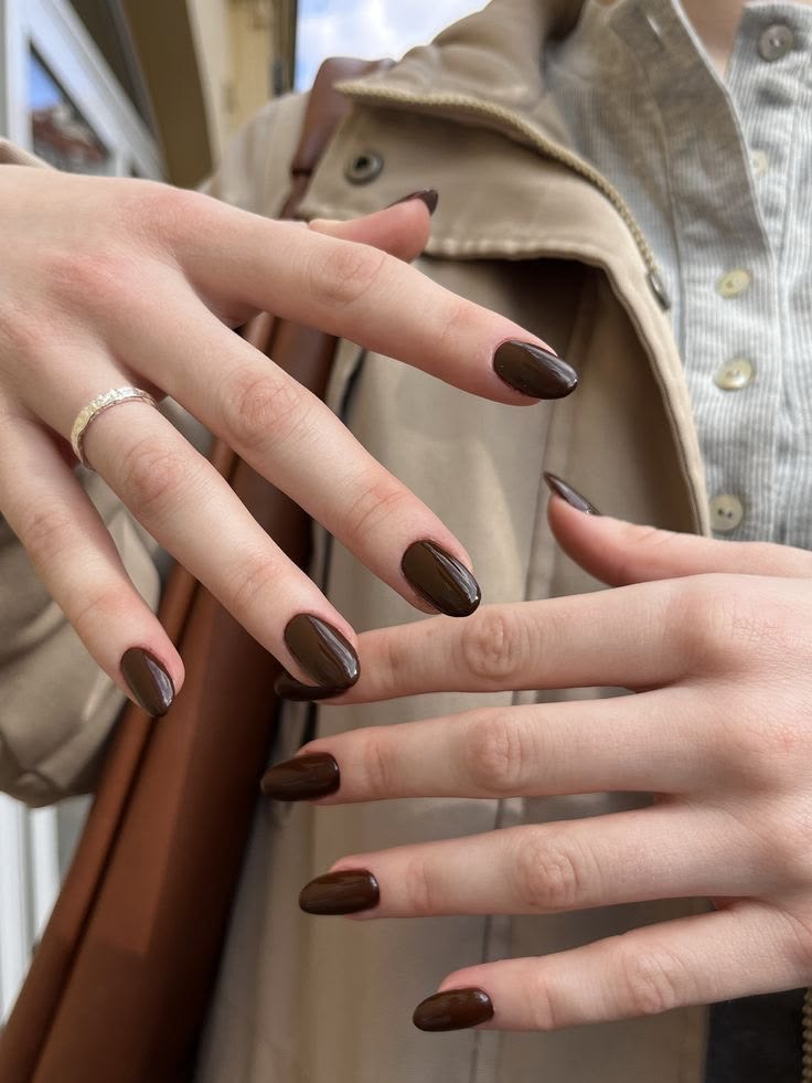 M&atilde;os femininas com unhas pintadas de marrom